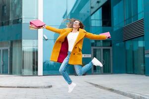 affaires femme avec achats Sacs habillé Jaune manteau sauter avec bonheur en plein air corporatif bâtiment Contexte photo