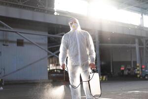homme habillé blanc protecteur salopette pulvérisation surface antibactérien désinfectant pulvérisateur pendant quarantaine photo