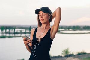 sans fil écouteurs fonctionnement femme sur aptitude entraînement. actif mode de vie athlète écoute à téléphone intelligent la musique téléphone app avec dans l'oreille équipement sur plage. photo