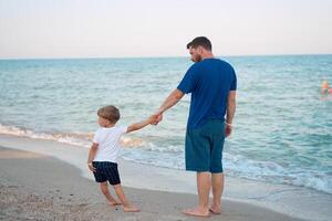 père fils dépenses temps ensemble mer vacances Jeune papa enfant peu garçon en marchant plage photo