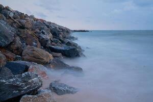 Roche digue dans le mer dans le Matin photo