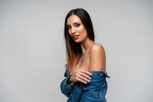 magnifique caucasien fille dans une denim veste posant dans le studio sur une blanc Contexte. photo