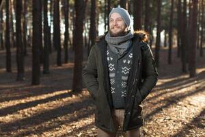 proche en haut portrait de une barbu branché touristique dans gris capuche homme dans le lumière du soleil photo