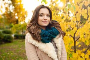 une magnifique Jeune fille des promenades par le l'automne parc sur le Contexte de vivement coloré feuilles photo