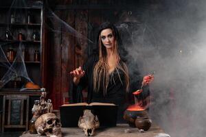 Halloween, sorcière utilisation la magie livre et chaudron préparer poison ou l'amour potion photo