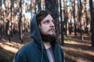 homme est permanent dans le forêt et juste relaxant habillé comme potes dans foncé bleu goodie photo