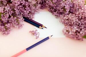 feuilles de blanc nettoyer papier et printemps fleurs lilas, sur une rose Contexte. photo