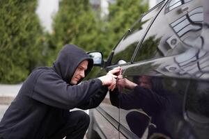 voiture jacking voleur voler voiture rupture porte criminel emploi cambrioleur détournements auto voleur noir cagoule sweat à capuche en essayant Pause dans véhicule Tournevis rue la criminalité la violence bandit voleur voiture photo