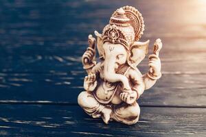 hindou Dieu ganesh sur noir Contexte. statue sur en bois table photo