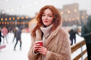 Jeune magnifique roux fille taches de rousseur la glace patinoire sur Contexte. jolie femme frisé cheveux portrait en marchant sur Nouveau année juste photo