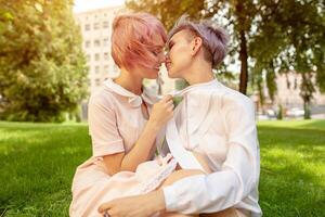 multiracial lesbienne couple mensonge sur le herbe. elles ou ils sont deux Jeune femmes repos à parc. un est caucasien et le autre est asiatique. elles ou ils sont souriant et portant été vêtements. photo