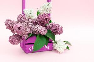 lilas fleurs bouquet dans une violet en bois panier plus de rose Contexte. magnifique violet lilas fleur encore la vie Pâques frontière conception sur en bois tableau. beauté parfumé lilas fleurs bouquet avec copie espace photo