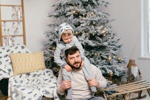 vacances Noël Beau père en jouant avec petit mignonne fils près décoré Nouveau année arbre à Accueil photo