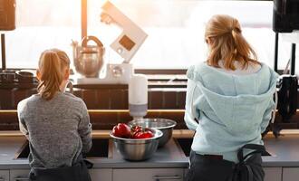 culinaire classe. deux les filles en train de préparer des légumes dans le cuisine. photo de le retour