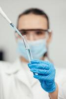 médical recherche laboratoire. une scientifique travaux avec une pipette et une tester tube. scientifique laboratoire de biotechnologie, développement de médicament et recherche dans chimie, biochimie et expériences photo