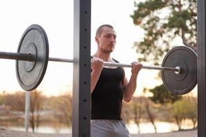 homme avec haltère Extérieur Gym sur la nature dans parc. photo