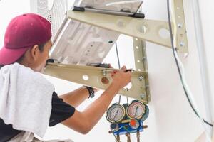 technicien homme en utilisant une clé à réparer et installer Nouveau air Conditionneur, Masculin technicien un service pour réparation et entretien de air conditionneurs photo