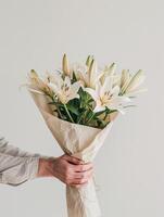 ai généré fermer de une main en portant une enveloppé de papier bouquet de blanc fleurs de lys photo