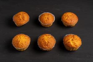 appétissant muffins supporter sur une table Haut voir. traditionnel des pâtisseries sur une foncé Contexte minimalisme. photo