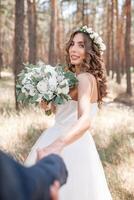 suivre moi mon l'amour concept. attrayant Jeune femme habillé dans blanc mariage robe en portant main de sa copain et en marchant sur le magnifique jardin à content futur photo