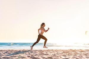 sportif blond femme fonctionnement océan plage. Jeune caucasien femelle exercice en plein air fonctionnement rivage. concept de en bonne santé fonctionnement et en plein air exercer. photo