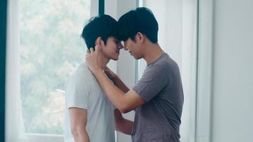 couple gay asiatique debout et s'embrassant près de la fenêtre à la maison. jeunes hommes lgbtq asiatiques s'embrassant heureux se détendre se reposer ensemble passer du temps romantique dans le salon de la maison moderne le matin concept. photo