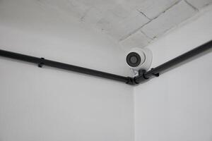 blanc rond vidéosurveillance caméra installée dans le coin sur une blanc mur. photo