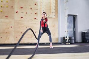 Gym bataille corde femme endurance formation athlète gars aptitude exercice endurance intérieur entraînement. photo