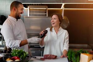 Beau Jeune africain chef est cuisine ensemble avec le sien caucasien petite amie dans le cuisine en utilisant rouge du vin comme un ingrédient. photo