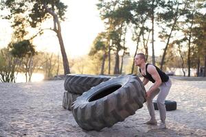 fort homme formation faire des exercices levage grand pneu Extérieur DIY salle de sport. photo