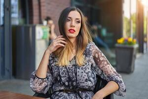 magnifique élégant Jeune fille avec foncé teint longue cheveux est assis à une table été Extérieur café attendre pour sa petit ami. photo