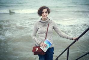 glamour portrait de le Jeune magnifique femme dans cuir bottes sur le banque de une plage photo