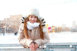 moyen tirer portrait de romantique européen Dame porte longue élégant hiver veste et marrant duveteux chapeau dans neigeux journée. Extérieur photo de inspiré blond femme profiter hiver ville.