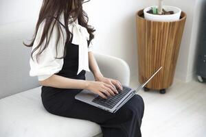 une Japonais femme dactylographie portable par éloigné travail dans le Bureau sans visage composition photo