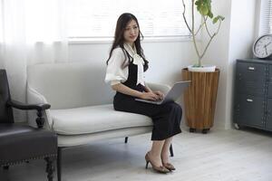 une Japonais femme vérification téléphone intelligent par éloigné travail dans le Accueil Bureau photo