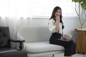 une Japonais femme vérification téléphone intelligent par éloigné travail dans le Accueil Bureau photo