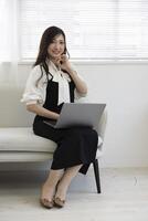 une Japonais femme vérification téléphone intelligent par éloigné travail dans le Accueil Bureau photo