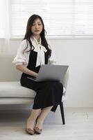 une Japonais femme vérification téléphone intelligent par éloigné travail dans le Accueil Bureau photo