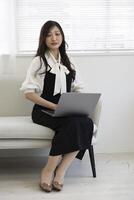 une Japonais femme vérification téléphone intelligent par éloigné travail dans le Accueil Bureau photo