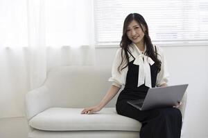 une Japonais femme vérification téléphone intelligent par éloigné travail dans le Accueil Bureau photo