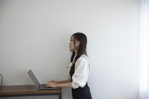 une Japonais femme vérification téléphone intelligent par éloigné travail dans le Accueil Bureau photo