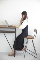 une Japonais femme vérification téléphone intelligent par éloigné travail dans le Accueil Bureau photo