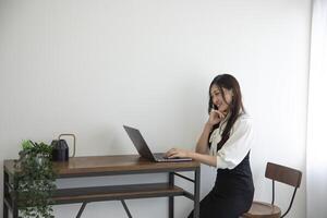 une Japonais femme vérification téléphone intelligent par éloigné travail dans le Accueil Bureau photo