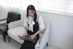 une Japonais femme vérification téléphone intelligent par éloigné travail dans le Accueil Bureau photo