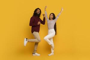 homme et femme sauter avec élevé bras sur Jaune photo