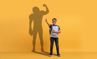 une souriant Jeune garçon avec des lunettes et une sac à dos détient école papiers photo