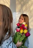 Fratrie ou double journée. aux femmes ou de la mère journée. portrait de deux souriant peu fille avec une bouquet de tulipes. espace pour texte. photo