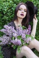 une à la mode fille avec foncé cheveux, une printemps portrait dans lilas tons dans été. brillant professionnel se maquiller. photo