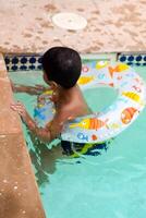 content Indien garçon nager dans une piscine, enfant portant nager costume le long de avec air tube pendant chaud été les vacances, les enfants garçon dans gros nager bassin. photo