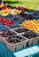 ai généré Frais baies et fruit affiché sur une table à une ensoleillé Extérieur marché photo